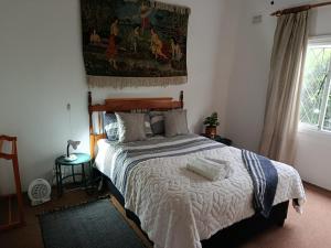 um quarto com uma cama e uma tapeçaria na parede em Serendipity-on-Symmonds Cottage em Howick