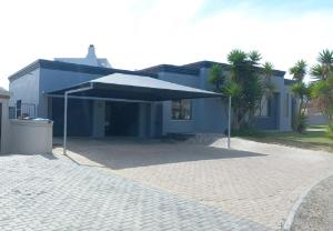 a blue house with a large umbrella in front of it at Linaria Beach House in Britannia Bay