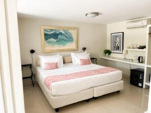 a bedroom with a large white bed with pink pillows at Casa Artista By Kresna Hospitality in Seminyak