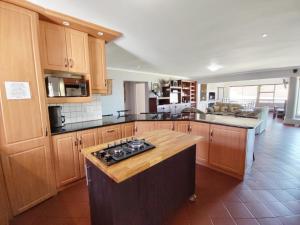 a kitchen with wooden cabinets and a stove top oven at Linaria Beach House in Britannia Bay