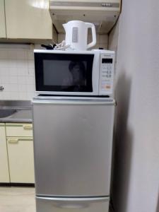 a microwave on top of a refrigerator in a kitchen at SunandMoonホテル401 in Tokyo