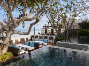 an infinity pool with chairs and tables and a view of the ocean at V Villas Hua Hin - MGallery Collection in Hua Hin