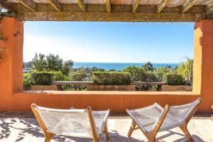 two chairs on a porch with a view of the ocean at The Villino at Cypress Ridge Estate - Stay Waiheke in Onetangi