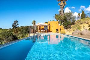 a swimming pool in front of a house at The Villino at Cypress Ridge Estate - Stay Waiheke in Onetangi