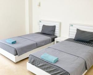 2 bedden in een witte kamer met blauwe kussens bij Jommalai Boutique Hotel in Ban Nong Chaeng