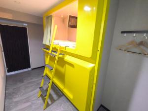 ein gelbes Etagenbett in einem Zimmer mit einem Schrank in der Unterkunft Hotel Shin-Imamiya in Osaka