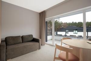 a living room with a couch and a table at Hidden Coast - Premium Seaside Apartments with Pool, 2-Minute Walk to the Beach in Łukęcin