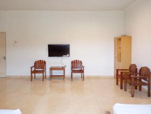 een kamer met stoelen en een televisie aan de muur bij Hotel Intan Sampang Banyumas RedPartner 
