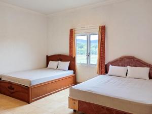 twee bedden in een kamer met een raam bij Hotel Intan Sampang Banyumas RedPartner 