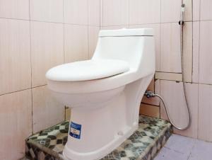 een wit toilet in een badkamer met een slang bij Hotel Intan Sampang Banyumas RedPartner  +25 foto's