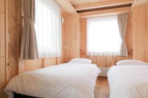 two beds in a room with a window at SMA MO inn Chitose in Chitose