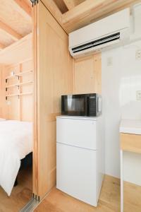 a tiny house with a microwave and a bed at SMA MO inn Chitose in Chitose