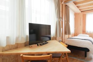 a room with a television and a table with a bed at SMA MO inn Chitose in Chitose