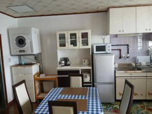 a kitchen with white cabinets and a table and a microwave at Miyagi Apartment Tomari in Naha
