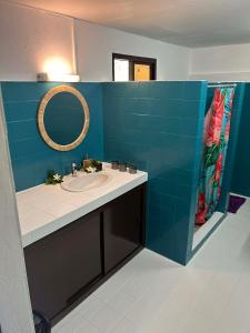 a bathroom with a sink and a blue tiled wall at Pension Hibiscus Taha'a in Vaitoare