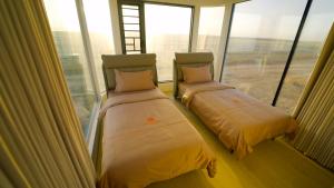 two beds in a room with large windows at Tegri Gobi Resort  +14 photos