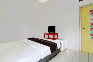 ein Schlafzimmer mit einem Bett und einem TV auf einem Tisch in der Unterkunft OYO 95065 Villa Ade in Campaka
