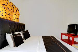 ein Schlafzimmer mit einem schwarz-weißen Bett und einem Fernseher in der Unterkunft OYO 95065 Villa Ade in Campaka + 26 Fotos