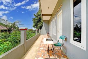 einen Balkon mit einem Tisch und einem Stuhl darauf in der Unterkunft OYO 95065 Villa Ade in Campaka