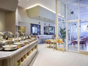 Un restaurante con línea de buffet con mesas y sillas. en Ibis Styles Jakarta Mangga Dua Square, en Yakarta