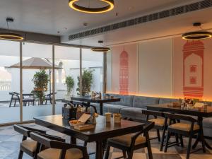 JāmbにあるThe Hosteller Bam Jaipur, Hawa Mahalのテーブルと椅子とソファのあるレストラン