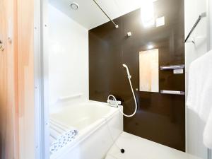a bathroom with a white tub and a black wall at SMA MO inn Omitama in Omitama