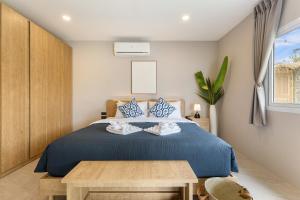 a bedroom with a blue bed and a table at Little Me Beachfront Villa in Nathon Bay