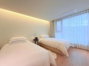 2 camas num quarto com uma janela em 제주 신성의 숲 웰니스 호텔 em Haean mais 98 fotografias