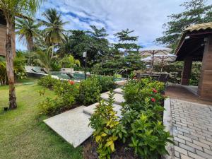 een tuin met bloemen en planten en een terras bij Condomínio Residencial Tiê in Camassari