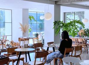 제주 신성의 숲 웰니스 호텔 في Haean: امرأة تجلس على طاولة في مطعم