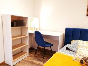 a bedroom with a desk and a blue chair next to a bed at Le saphire St Affrique hyper centre ville in Saint-Affrique +5 photos