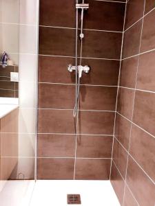 a shower in a bathroom with brown tiles at Le saphire St Affrique hyper centre ville in Saint-Affrique