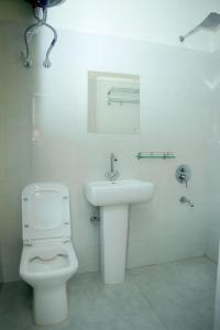 a white bathroom with a toilet and a sink at Mareenda's Haven in Shillong