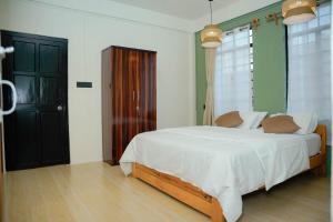 a bedroom with a white bed and a black cabinet at Mareenda's Haven in Shillong