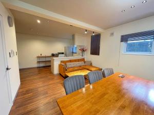 een woonkamer met een tafel en een keuken bij KUSUO HOUSE Roji in Sapporo