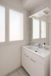 une salle de bain blanche avec un lavabo et deux fenêtres dans l'établissement Studio cosy à 5 min de la mer, à Antibes