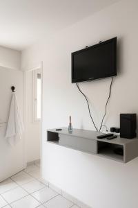 un salon avec une télévision sur un mur blanc dans l'établissement Studio cosy à 5 min de la mer, à Antibes