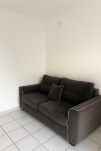 un canapé marron avec un coussin sur un mur blanc dans l'établissement Studio cosy à 5 min de la mer, à Antibes