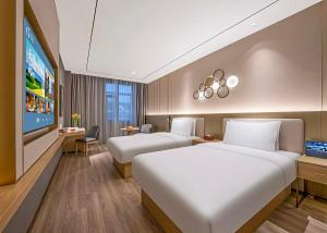 a hotel room with two beds and a flat screen tv at Orange Nanjing Baijia Lake Xiaolongwan Subway Station Hotel in Jiangning +26 photos