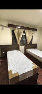 a bedroom with two beds and a window at TUYU Chhye in Kathmandu