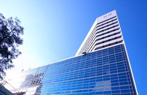 a tall glass building with a blue sky in the background at Hotel Keihan Kyobashi Grande in Osaka