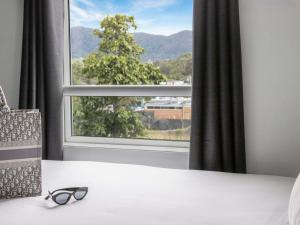 a pair of glasses sitting on a bed in front of a window at Coffs Harbour Budget Stay in Coffs Harbour