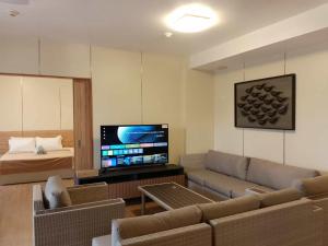 Luntian Luxury Condo in Tagaytay في Iruhin: غرفة معيشة مع أريكة وتلفزيون بشاشة مسطحة +صورتان