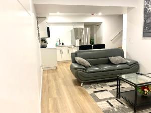 a living room with a black leather couch and a kitchen at Royal Oak in Winnipeg