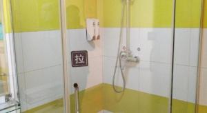 a shower in a bathroom with a sign on the wall at 7 Days Inn Enshi Xueyuan Road Shinan Ancient City in Enshi