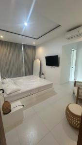 a white bedroom with a bed and a tv at Villa Buho Ungasan - Luxury Villa 4br in Ungasan +13 photos