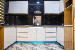cocina con armarios blancos y suelo de mármol en De Groove Apartment, en Addo