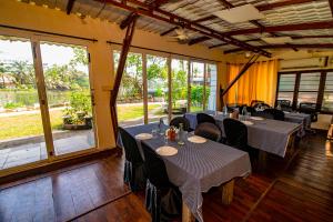 a dining room with tables and chairs and large windows at Mia Riaan Lake View Resort in Ernakulam