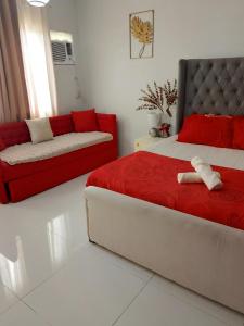 una camera da letto con un letto rosso e un divano di spacious condo at camella manors unit 5m a Bacolod