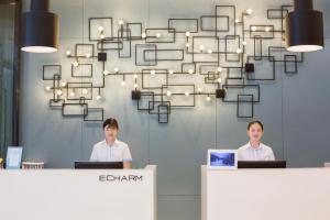 two men standing at a counter in an office with a chandelier at Echarm Hotel Changde Chaoyang D5 District in Changde